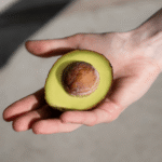 ręka z połówką awokado z pestką